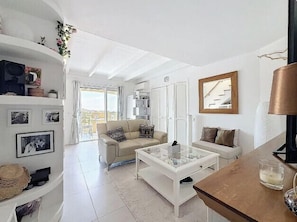 A modern living room with a sofa, a glass coffee table, and a wooden side table. - Apartment, terrace sea view in Saint-Raphaël (Saint-Raphaël)
