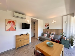 Ein modernes Wohnzimmer mit einer Couch, einem Fernseher, einem Holztisch mit einer Schüssel und einem Essbereich.