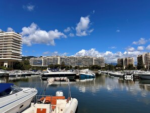 Ein Yachthafen mit vertäuten Booten, ein großes Hotelgebäude im Hintergrund und ein klarer, blauer Himmel.