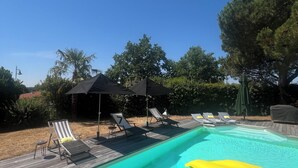 En pool med solstolar och parasoller.