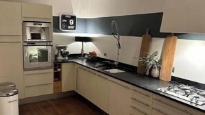 Ett modernt kök med mikrovågsugn, ugn, diskho och trägolv.