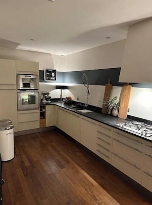 Uma cozinha moderna com micro-ondas, forno, pia e piso de madeira.