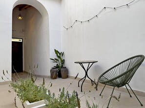 Ein Außenbereich mit Sitzgelegenheit, Tisch und Blumentöpfen.