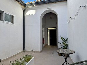 A narrow corridor with a tiled floor, an archway, a small table with a patterned top, and a potted plant. - La Casa de Juana I - Ole Solutions (Jerez de la Frontera)