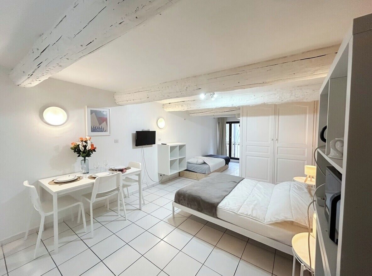 Ein modernes Schlafzimmer mit einem Bett, einem Schreibtisch, einem Stuhl, einem Fernseher und einem kleinen Tisch mit einer Lampe.