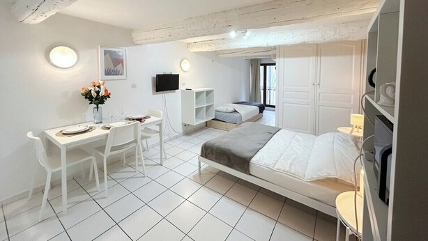 Ein modernes Schlafzimmer mit einem Bett, einem Schreibtisch, einem Stuhl, einem Fernseher und einem kleinen Tisch mit einer Lampe.