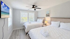 A hotel room with two beds, a ceiling fan, a TV, and a window with blinds. - San-Joy Retreat #9, 2BR Condo, Steps to Beach (Myrtle Beach)