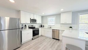A modern kitchen with white cabinetry, stainless appliances, and a light wood floor. - San-Joy Retreat #9, 2BR Condo, Steps to Beach (Myrtle Beach)
