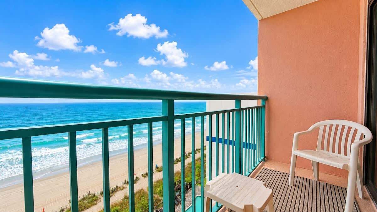 Ein Balkon mit Meerblick, ein weißer Stuhl und ein kleiner Tisch.