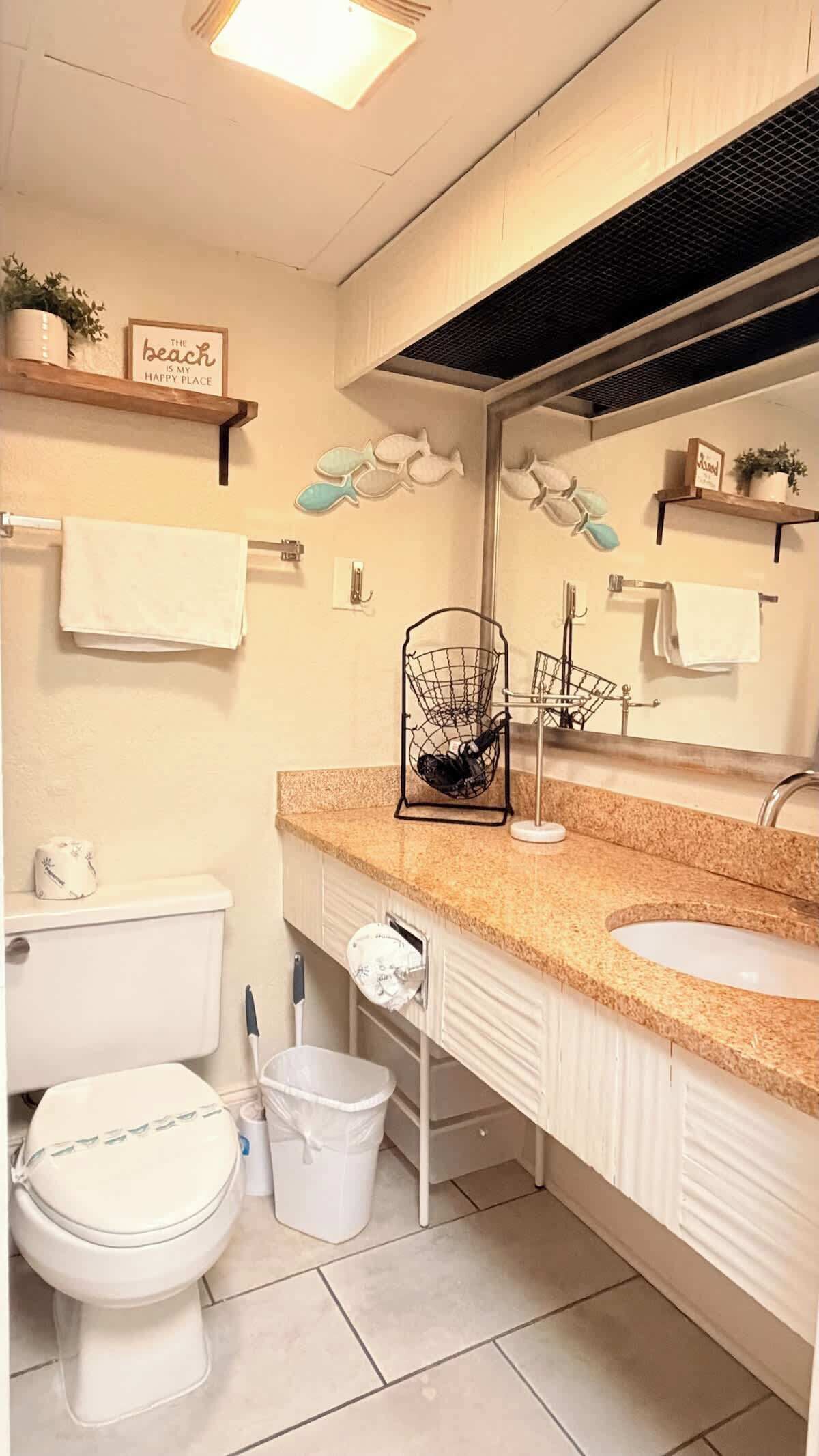 Ein Badezimmer mit Toilette, Waschbecken, Spiegel und Handtuchhalter.