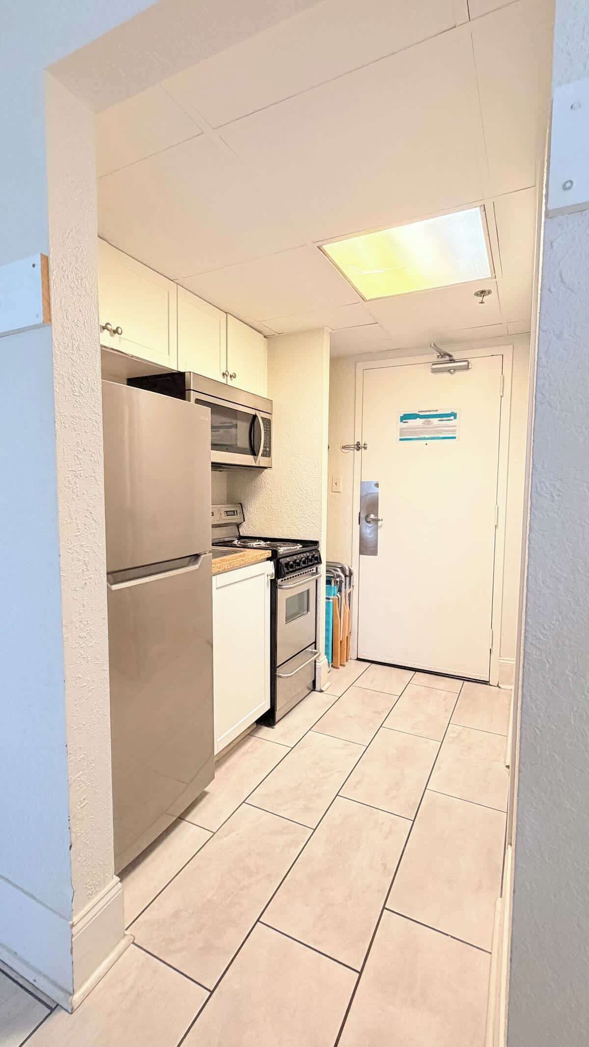 Una cocina compacta equipada con refrigerador, microondas, estufa y horno.