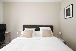 Ein Hotelzimmer mit einem Bett, zwei Nachttischlampen, einem Sessel und einem gerahmten Bild an der Wand.