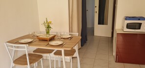 A dining table set with plates, cutlery, and a vase of flowers. - Apartment with terrace & pool (Palavas-les-Flots)