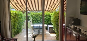 A patio with a table and chairs, a grill, and a TV on the wall. - Apartment with terrace & pool (Palavas-les-Flots)
