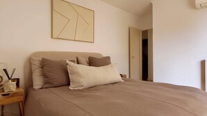 Ein Schlafzimmer mit einem Bett, Kissen, einem Nachttisch, einer Lampe und einer Heizung.