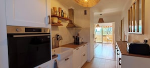 A kitchen with a built-in oven, a sink, wooden shelves, and a view to an outdoor area. - Bright apartment with a view in Saint-Raphaël (Saint-Raphaël)
