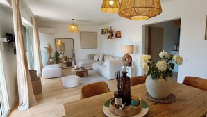 Ein modernes Wohnzimmer mit Essbereich, mit einem Holztisch, weißen Sofas und einem großen Spiegel.