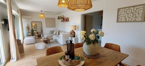 A modern living room with a dining area, featuring a wooden dining table, white sofas, and a large mirror. - Bright apartment with a view in Saint-Raphaël (Saint-Raphaël)
