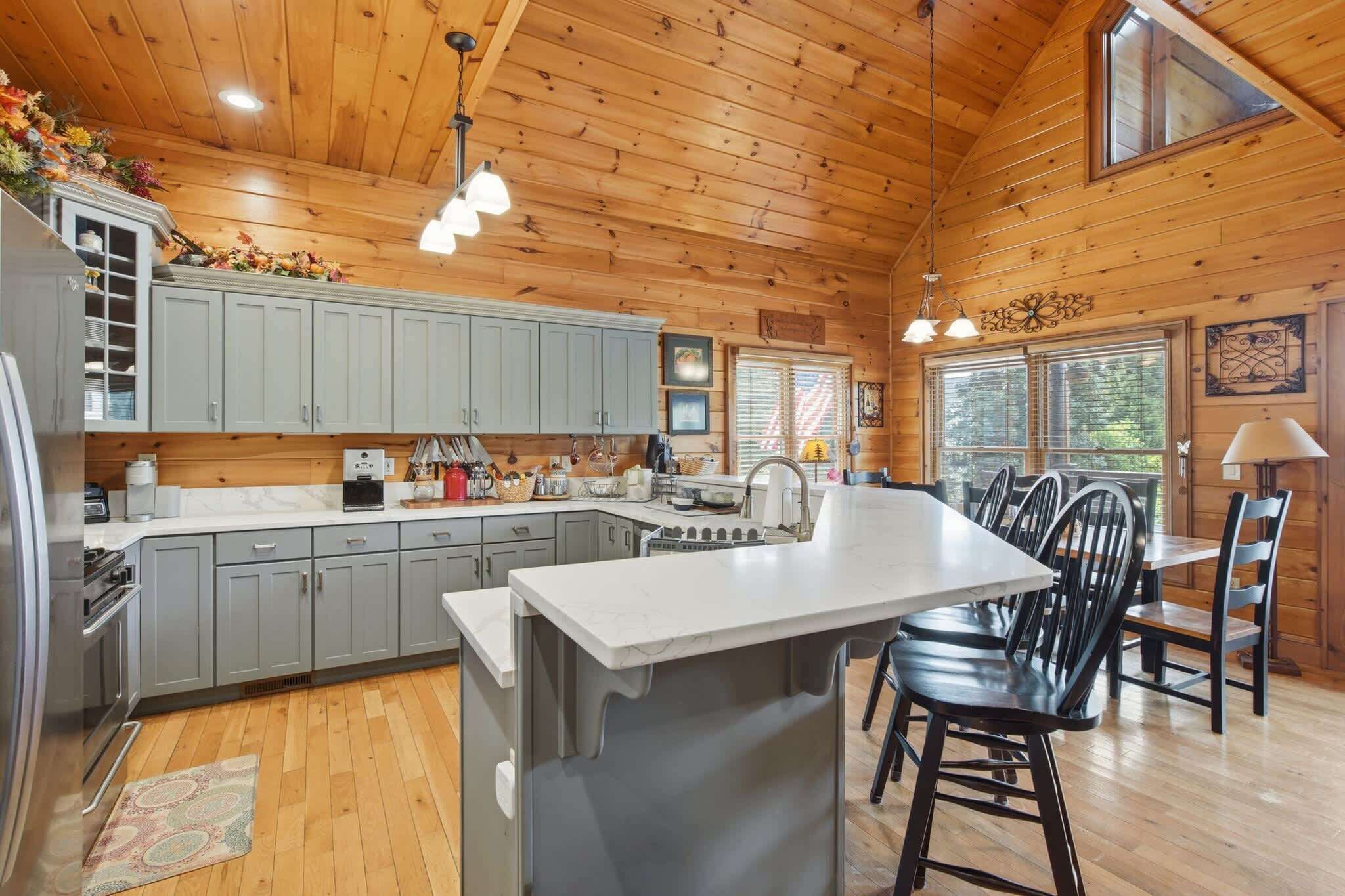 L’intérieur d’un chalet en bois comprend une cuisine, un coin repas et un grand îlot central doté de tabourets de bar.