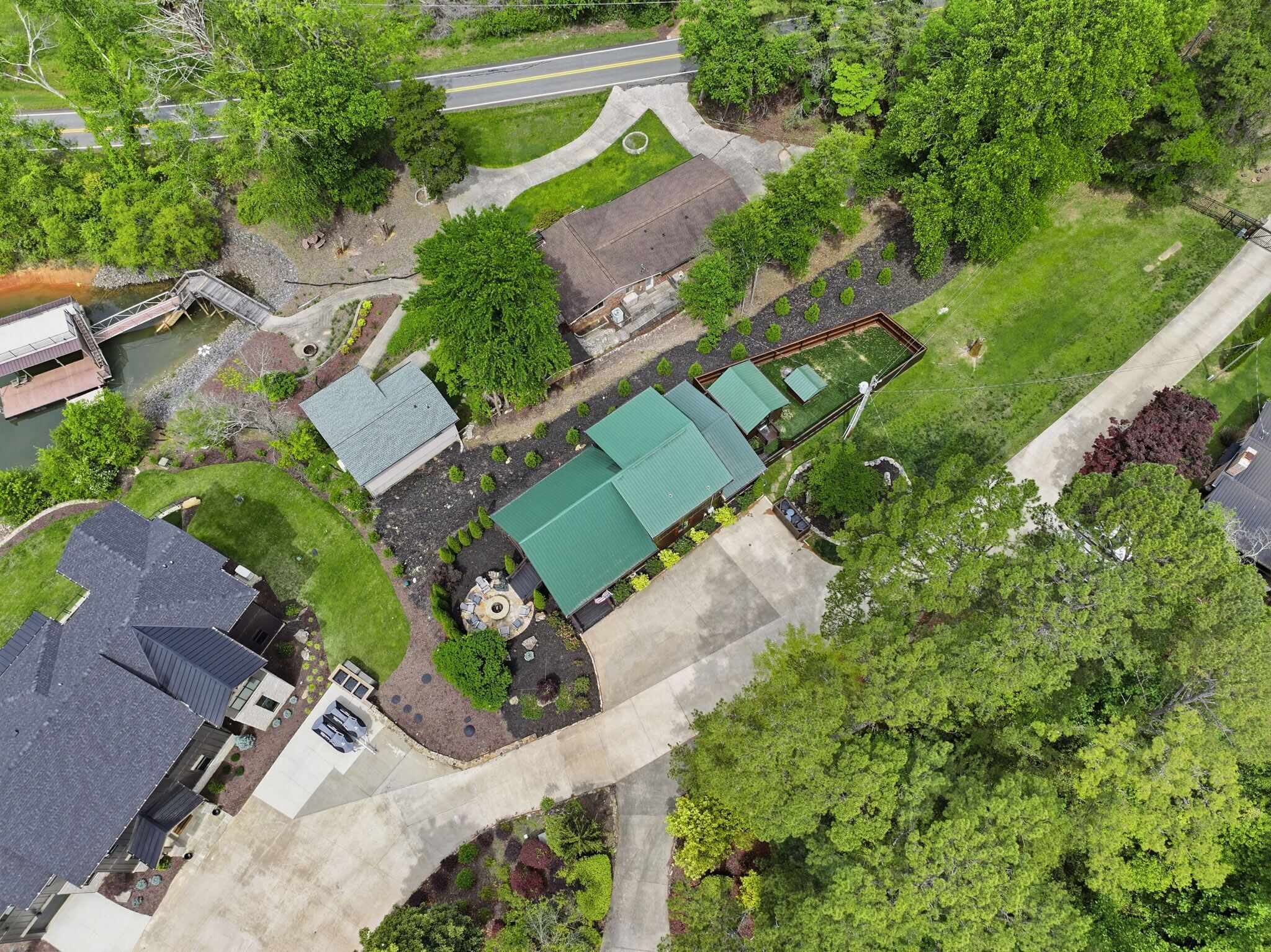 Una vista aerea di una zona residenziale con una casa dotata di tetto verde, vialetto e un piccolo giardino con zona salotto circolare.