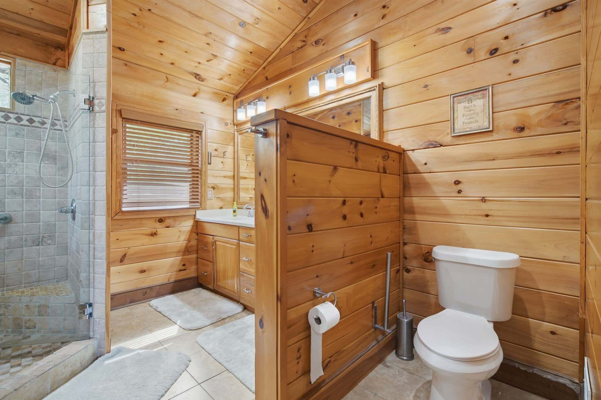 Een betegelde badkamer met douche, toilet en handdoekhouder.