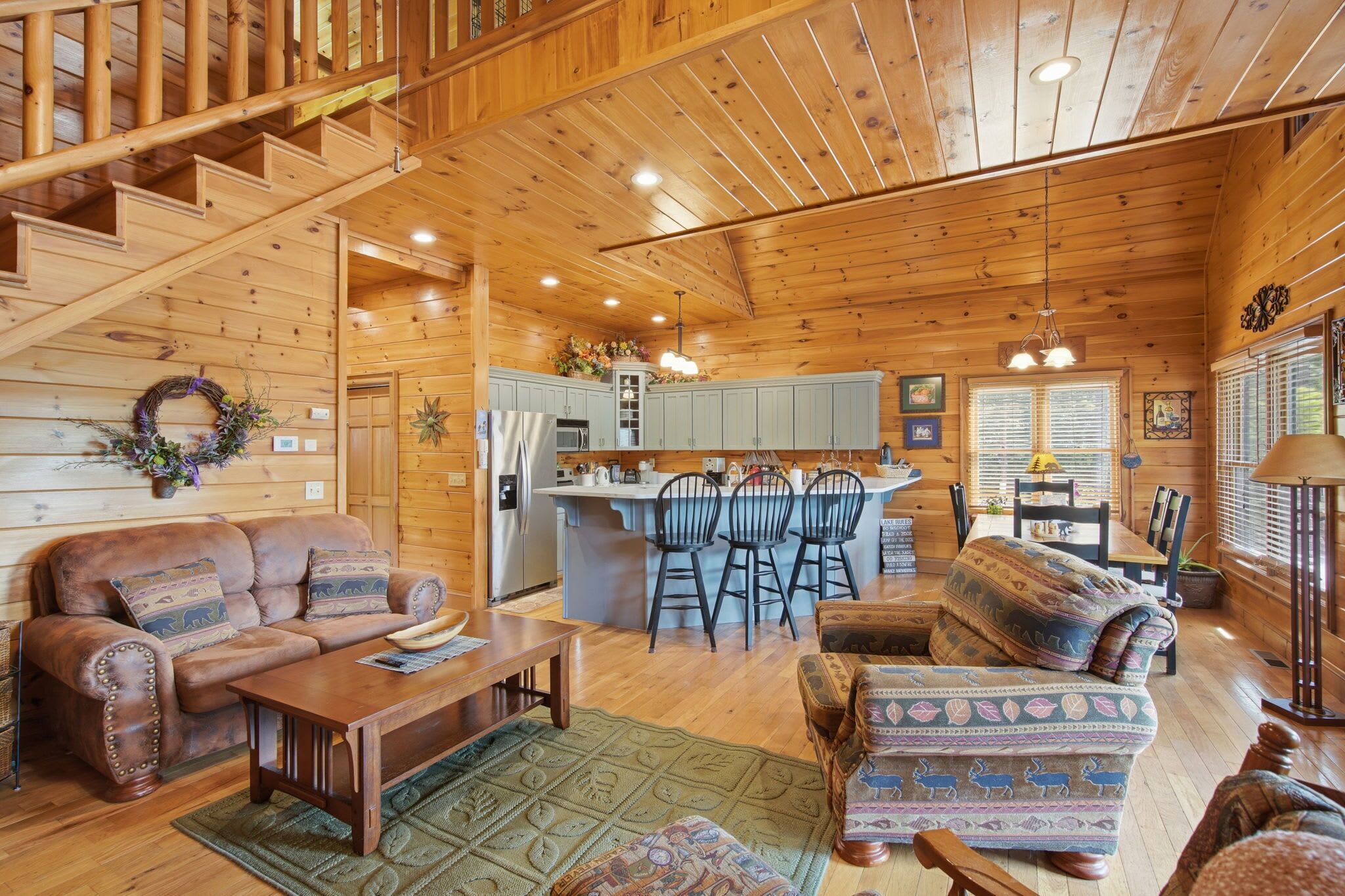 A wooden cabin interior with a living room, kitchen, and dining area.