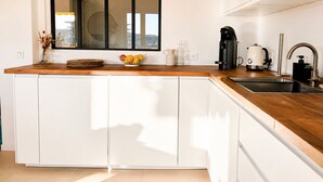 A modern kitchen with a wooden countertop, white cabinets, a large window, and a coffee maker. - apart with terrace and unobstructed view (Nice)