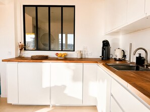 A modern kitchen with a wooden countertop, white cabinets, a large window, and a coffee maker. - apart with terrace and unobstructed view (Nice)