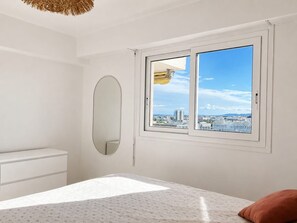 A bedroom with a bed, a dresser, a round mirror, and a window with a city view. - apart with terrace and unobstructed view (Nice)