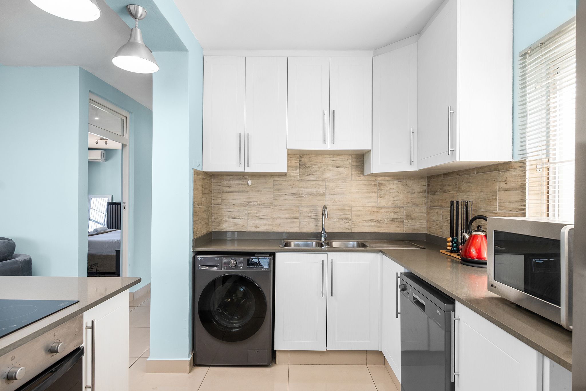 A compact kitchen with a washing machine, dishwasher, and microwave.