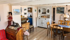 Un salón acogedor con un sofá rojo, muebles de madera, un radio y una zona de comedor con una mesa y sillas.