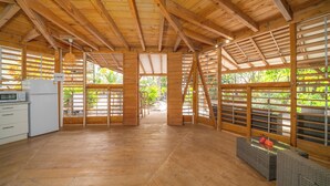 A spacious kitchen with wooden beams, a refrigerator, and a dining area with a table and chairs. - Bungalow Ixora, seaside (Les Anses-d'Arlet)