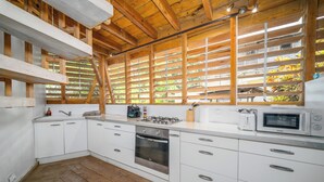 A modern kitchen with white cabinetry, a built-in oven, a gas stove, and a microwave. - Bungalow Ixora, seaside (Les Anses-d'Arlet)