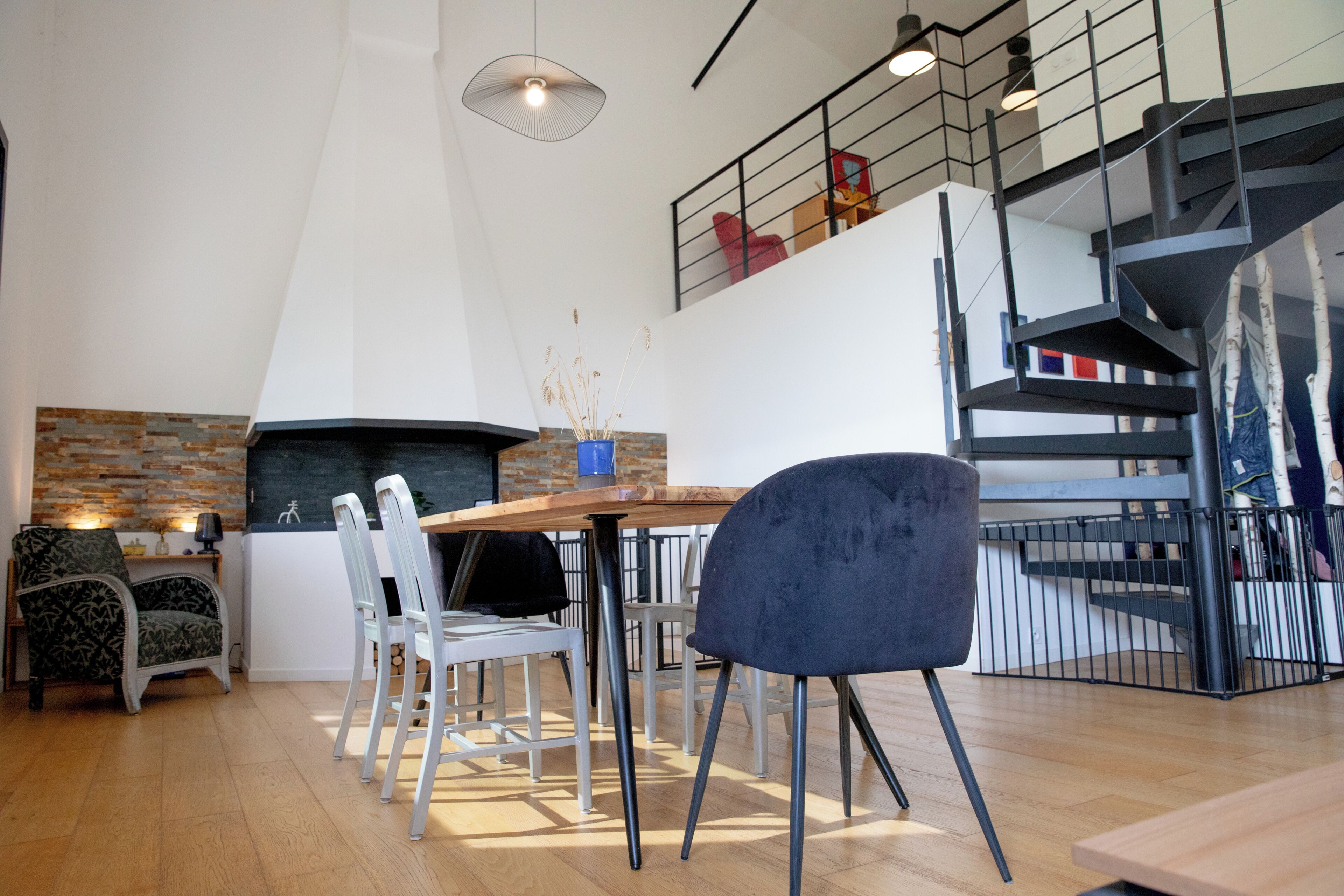 Un interior moderno con comedor, cocina que incluye un respaldo de piedra y una escalera.