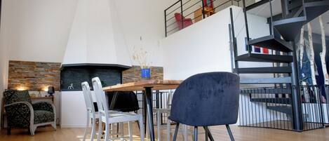 Un interior moderno con comedor, cocina que incluye un respaldo de piedra y una escalera.
