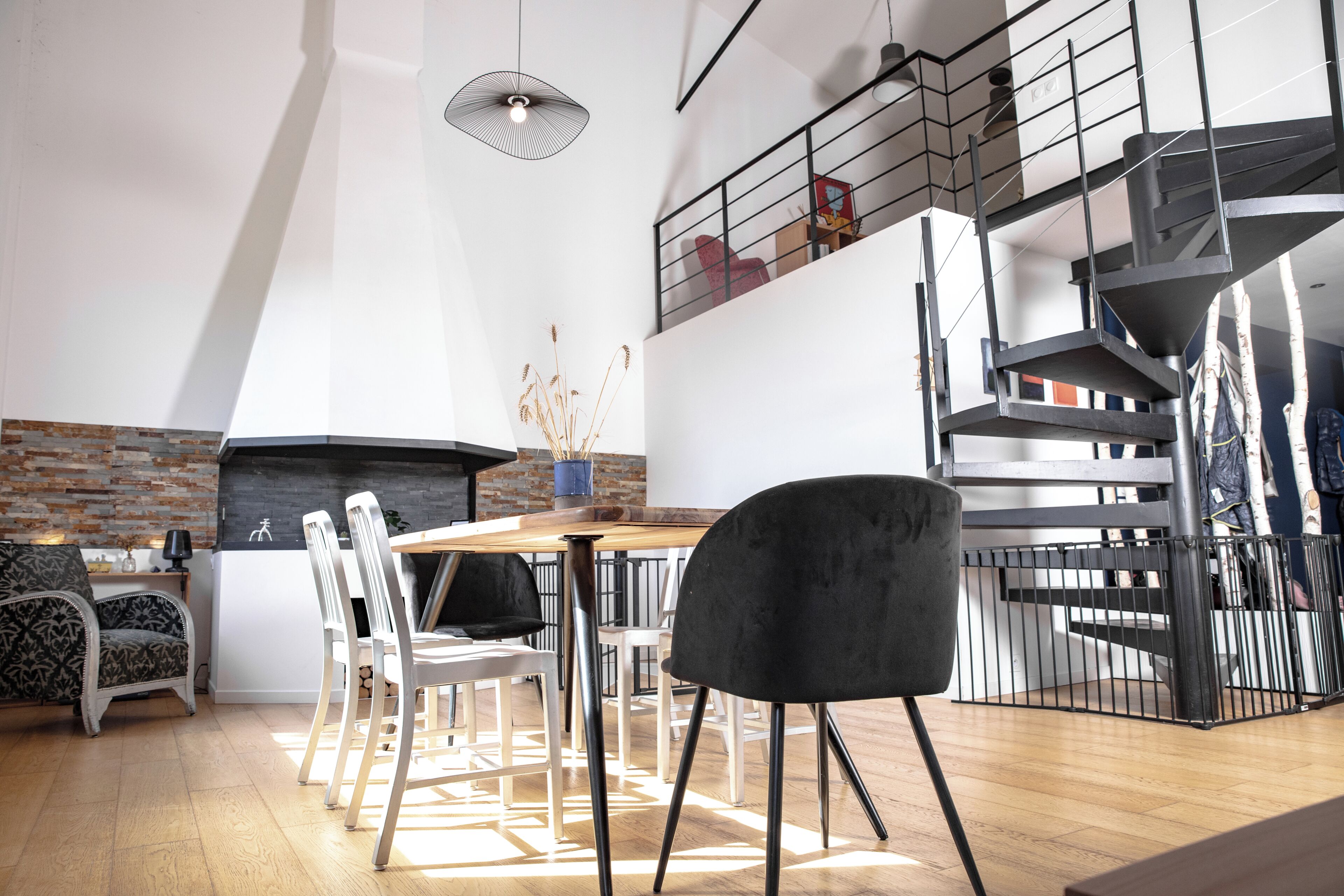 A modern interior with a dining area, staircase, and a fireplace.