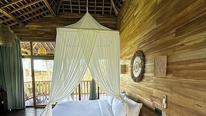 Une pièce en bois avec un lit, un petit tabouret et un ventilateur de plafond.