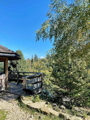 Eine Holzhütte mit Dach, einer Holzterrasse und einem Steinweg, der dorthin führt.