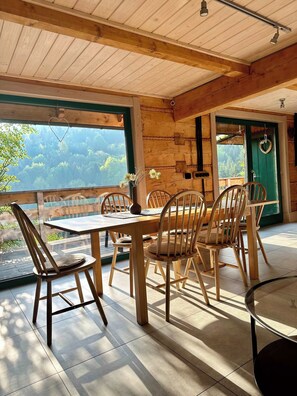 Comedor de madera con una mesa, sillas y vistas al exterior, además de una puerta verde.