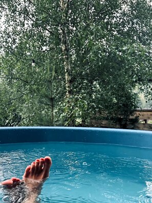 En pool med en persons fötter i vattnet, omgiven av träd.