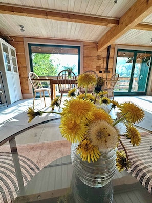 Et spiseområde med et glasbord, stole og en vase med gule blomster.