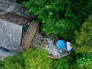 Vista aérea de un patio en la azotea con jacuzzi, mobiliario exterior y abundante vegetación.