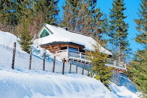 En stuga med ett snötäckt tak, en träkonstruktion och en balkong.