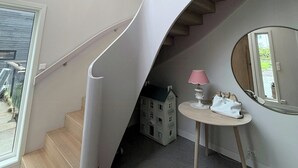 Ein modernes Interieur mit einer Wendeltreppe, einem runden Spiegel und einem kleinen Tisch mit einer Lampe.