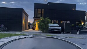Ein modernes Gebäude mit flachem Dach, einer Auffahrt und einem geparkten Auto davor.