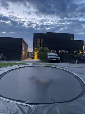 Ein modernes Gebäude mit flachem Dach, einer Auffahrt und einem geparkten Auto davor.