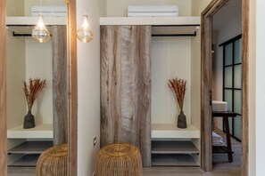 A modern bathroom with a wooden accent wall, a mirror, and two wicker stools. - Orion Sunset Villa (Erissos)