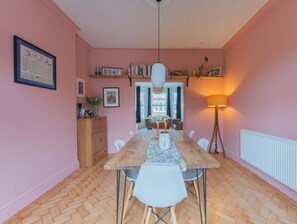 A dining area with a wooden table, white chairs, a hanging light fixture, and a radiator. - Grand Victorian home, 2 mins to Hoylake beach. Sleeps the whole family. (Hoylake)