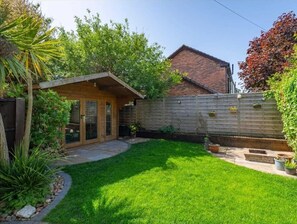 A backyard with a wooden deck, a brick house, and a fenced area. - Grand Victorian home, 2 mins to Hoylake beach. Sleeps the whole family. (Hoylake)