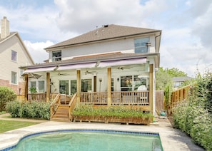 A two-story house with a covered patio, a swimming pool, and a garden. - Cozy House Retreat Near Texas Medical Center. (Houston)